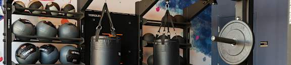 A gym with a punching bag, kettlebell, and weightlifting equipment.