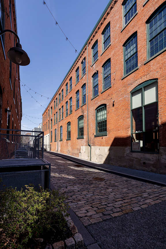 A brick building with green shutters and a metal gate.