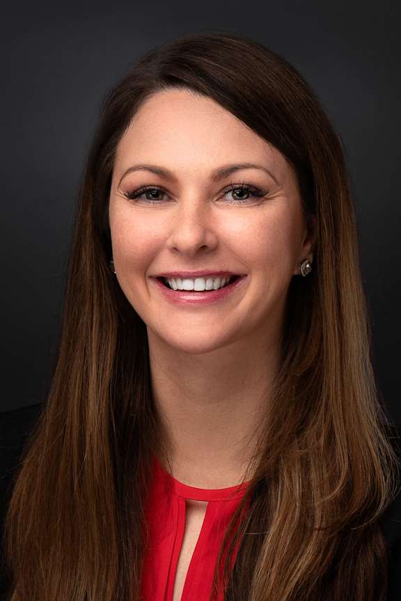 A woman with long brown hair wearing a red top.