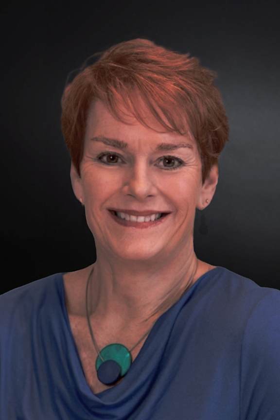 A woman with short hair and a blue top is smiling.