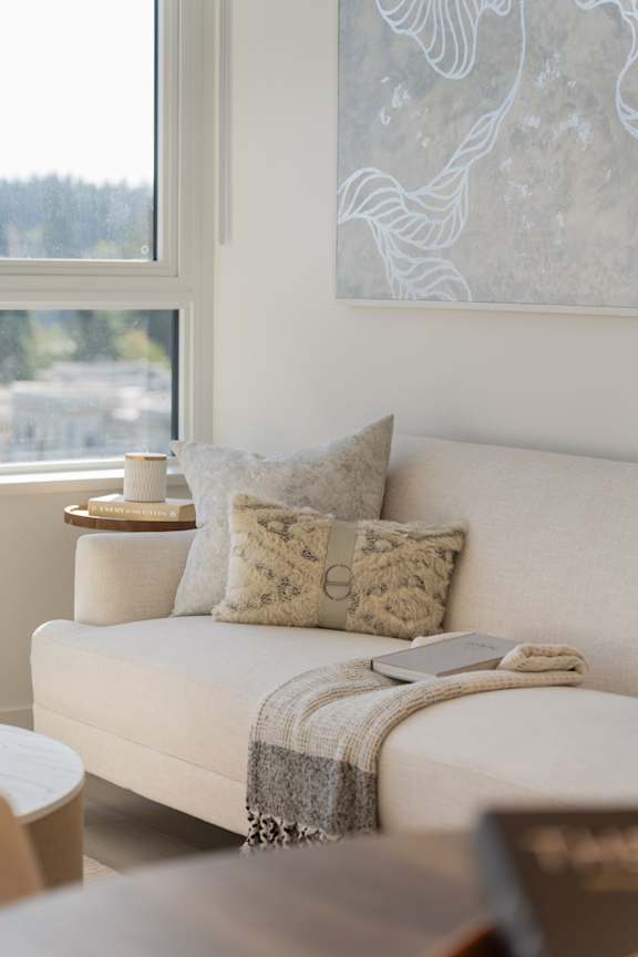 A white couch with a grey pillow and a blanket on it.