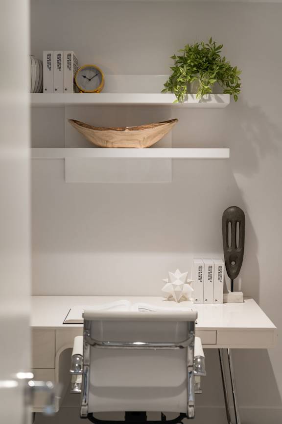 A white desk with a chair and a plant on top of it.