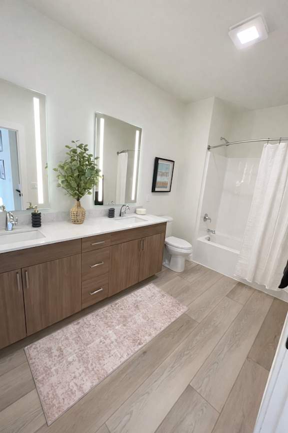 A bathroom with a white tub, sink, and a pink rug.