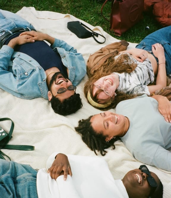 a group of people laying on a blanket on the grass