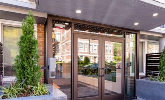A modern house entrance with a glass door and a wooden planter box.