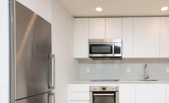 A modern kitchen with white cabinets and stainless steel appliances.