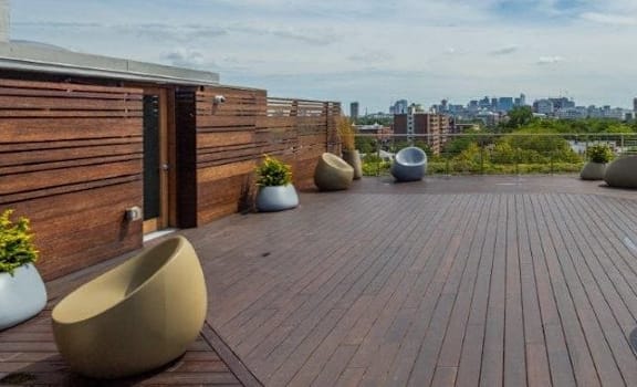 A wooden deck with several chairs and a city view in the background.