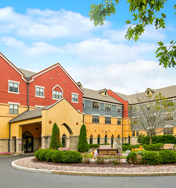 A large building with a red roof and a courtyard in front.