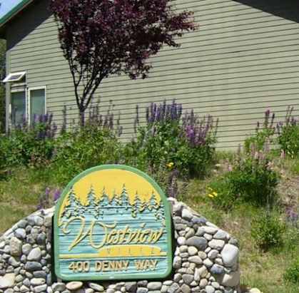 a house with a sign in front of a field of flowers