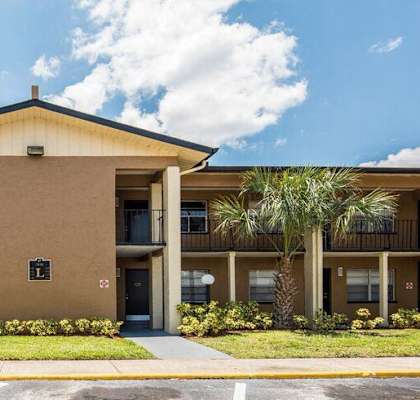 a building with palm trees in front of it  at Oak Manor Apartment Homes, Tampa, FL
