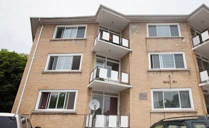 a brick apartment building with cars parked in front of it