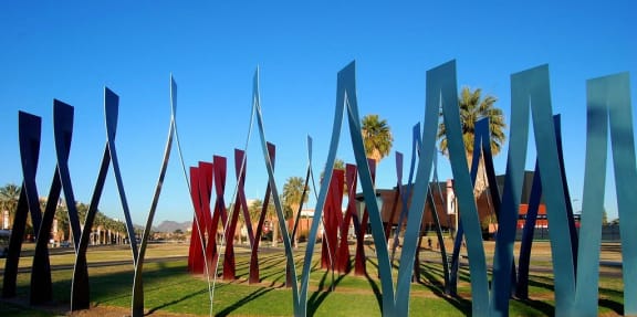 a shadow of a person taking a picture of a sculpture in a park