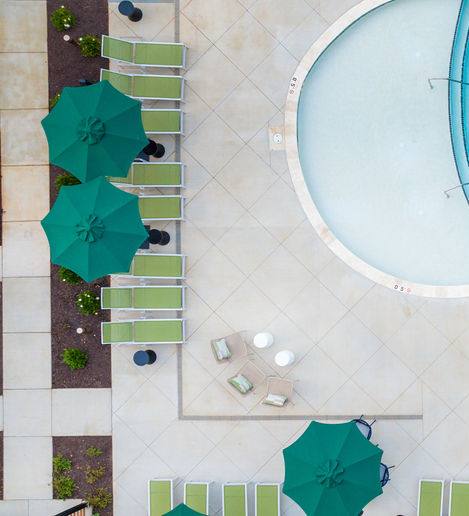 A large swimming pool surrounded by green and white umbrellas.