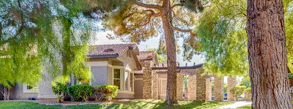 a house with a sidewalk and trees in front of it