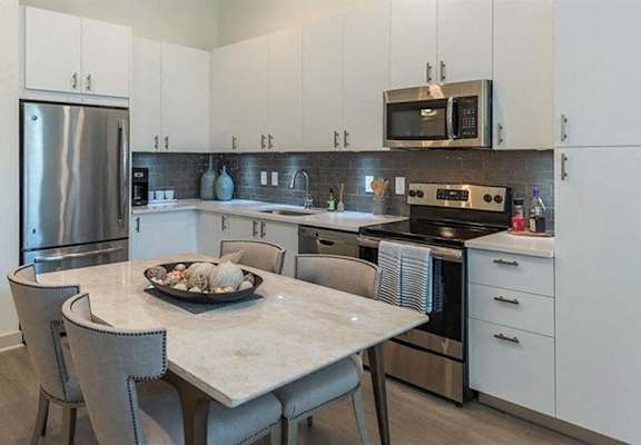 A kitchen with a stove top oven next to a table at 2000 West Creek Apartments in Richmond, Virginia 23238