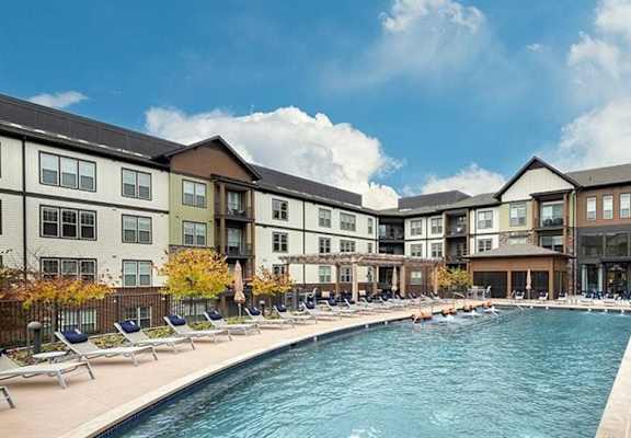 A swimming pool with chaise lounge chairs in front of a building at 2000 West Creek Apartments in Virginia 23238