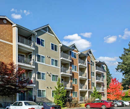 an apartment building with cars parked in a parking lot