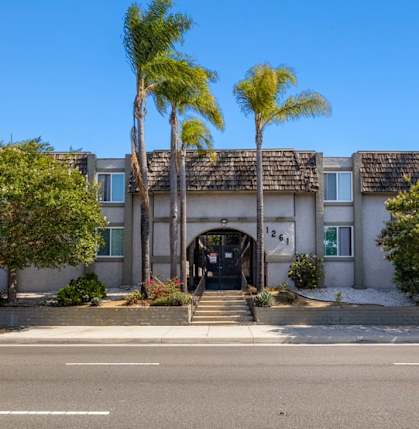 A building with palm trees in front of it and the words "Beach Front Property Management" on the bottom left.