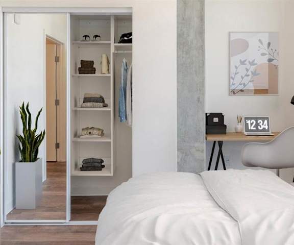 A bedroom with a white queen-size bed, desk, decorations, a plant, closet, and nightstands at Joy on 4th. 
