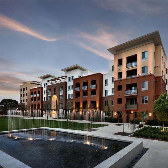 A couple sitting on a couch in a courtyard with a fire pit in the middle. at West Park Apartments, San Diego, California