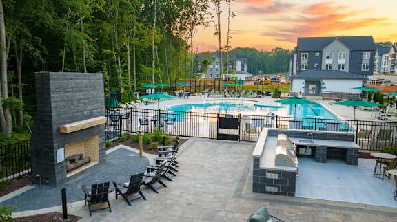 A backyard with a pool, patio furniture, and a fireplace.