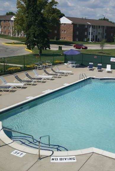 a swimming pool with chaise lounge chairs and a building in the background