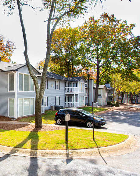 A white house with a grey roof is surrounded by trees.