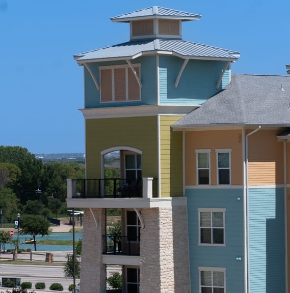 a large apartment building with two balconies and a large body of water in the background