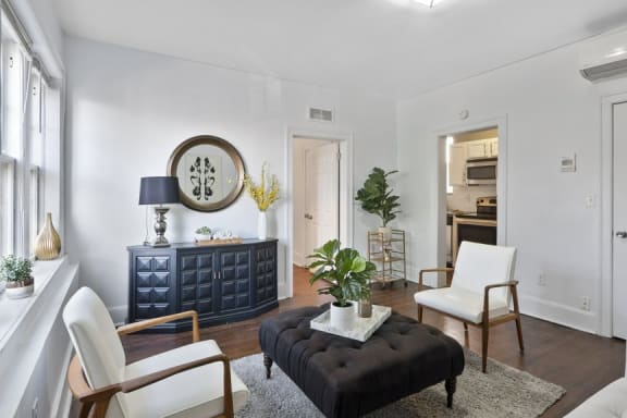 a living room with white walls and a black ottoman