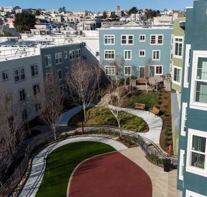 A view of a courtyard with a red track and a green lawn.