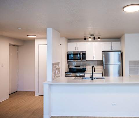 A modern kitchen with a white countertop and stainless steel appliances.