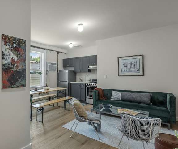A modern living room with a green couch and a painting on the wall.