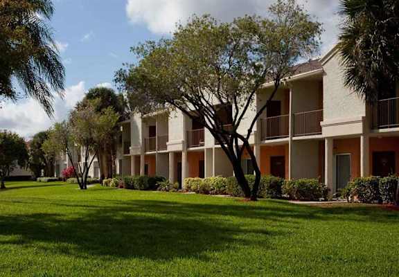 an apartment building with grass and trees in front of it at Waterford Park Apartment Homes, LLC, Lauderhill
