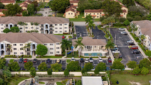 A large apartment complex with a pool and a parking lot.