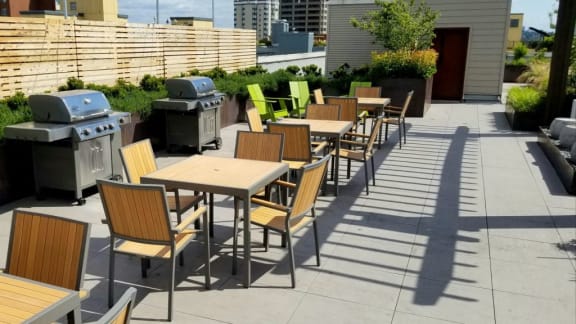 A patio with tables and chairs and barbecues.