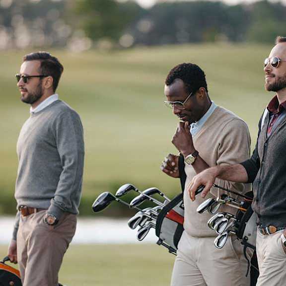 three men standing on a golf course with their bikes