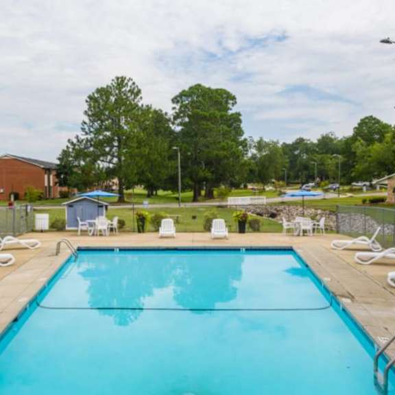 A large swimming pool surrounded by white lounge chairs.