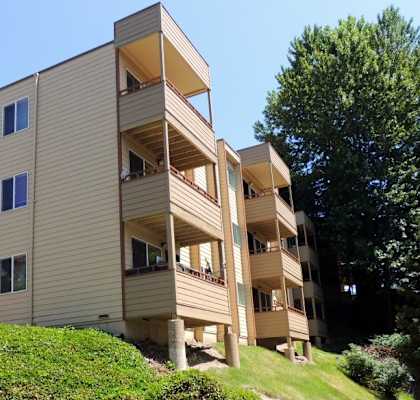 A beige apartment building with a green lawn in front.