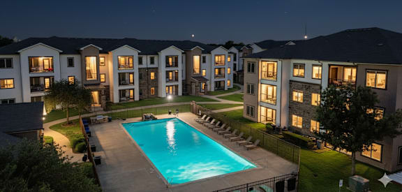 A moonlit night view of a swimming pool and apartment complex.