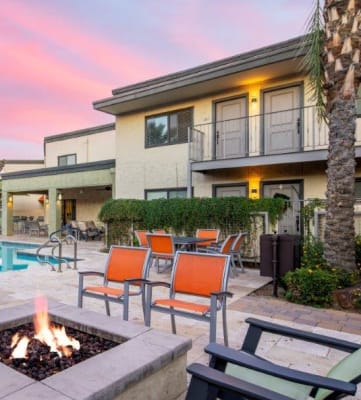 a backyard with a fire pit and lounge chairs