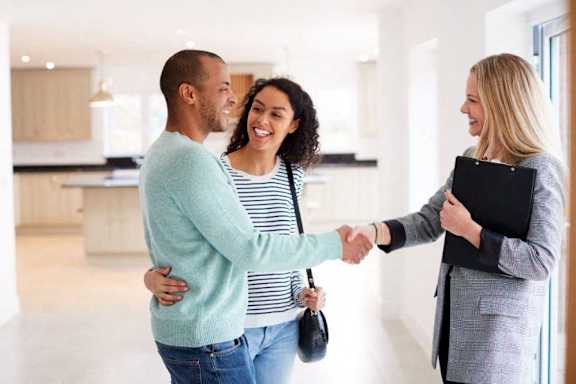 a man shaking hands with two women in an empty house