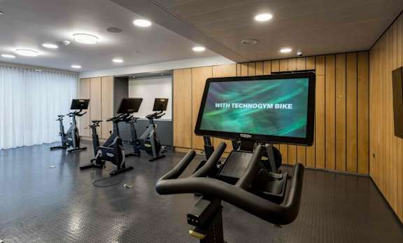 A gym with a screen displaying at Alameda Apartments, Wembley, HA9 0HS