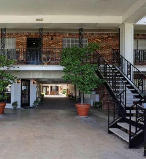 A courtyard with a black railing and a brick building.