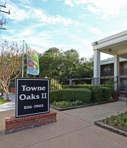 The image shows the entrance to Towne Oaks II with a sign and a brick wall.