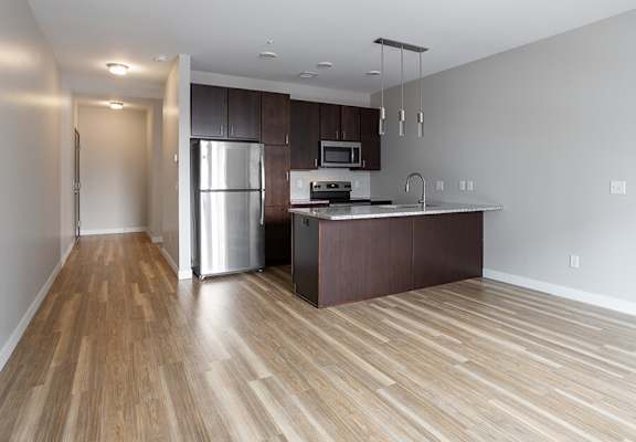 An empty kitchen with stainless steel appliances and wooden floors at RoCo Apartments in Fargo, ND 58102