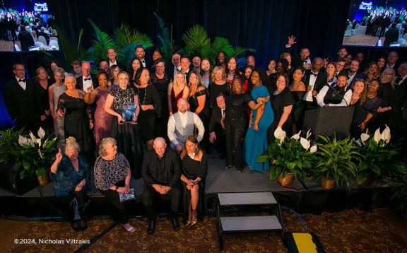 a large group of people posing for a photo on a stage