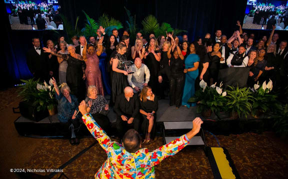 a group of people singing and raising their hands in the air at a party
