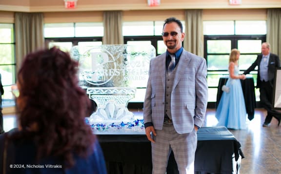 a man in a suit and tie standing in front of a cake