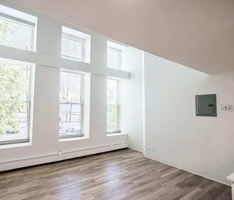 A room with wooden floors and three windows.