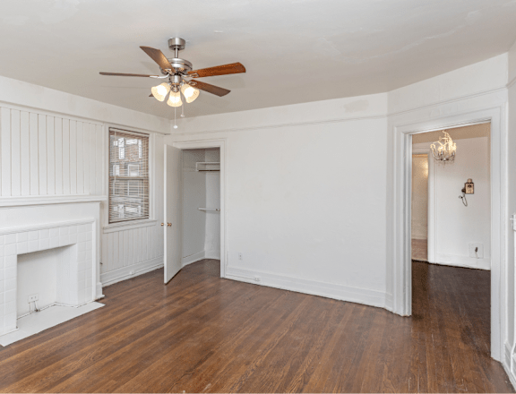a living room with white walls and a ceiling fan